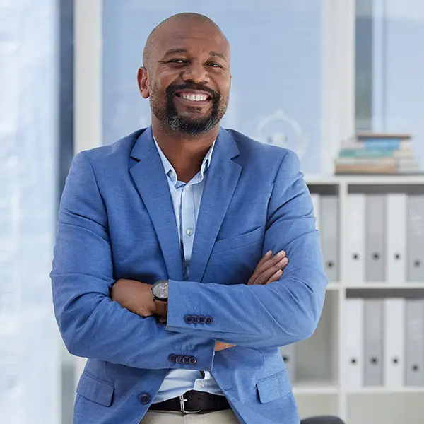 Confident businessman smiling with arms crossed in modern office