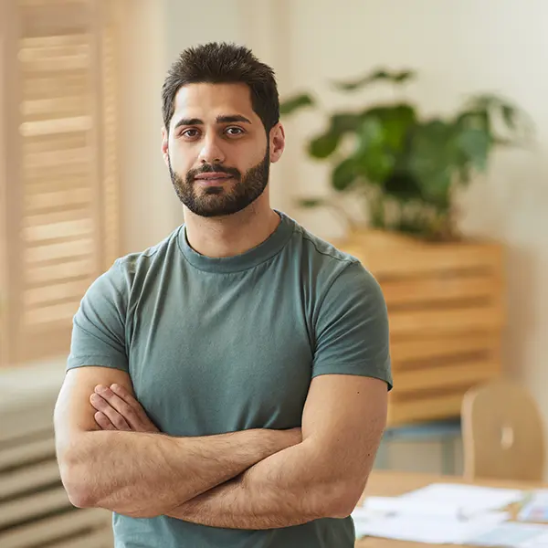 Confident man with crossed arms standing in a bright office space