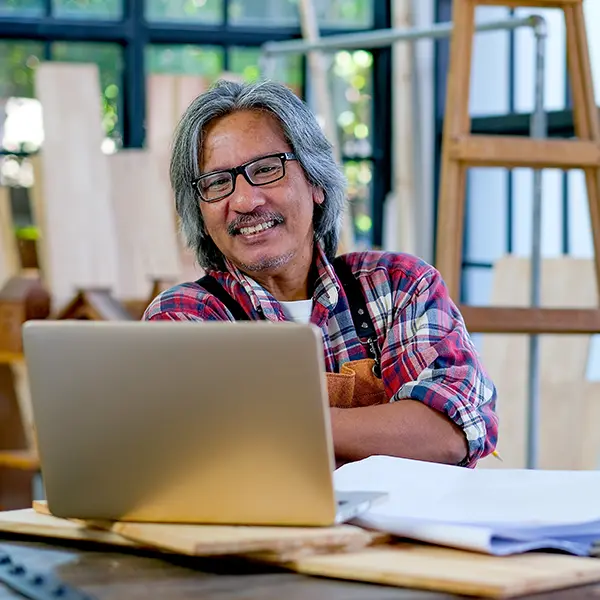 Smiling small business owner working on a laptop in a workshop